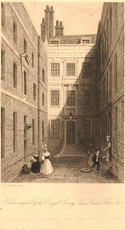 Print. A tall, narrow etching shows a tall, narrow house front, from which buildings extend towards us to each side of what feels like an alleyway. A pair of women in dresses and bonnets converses to our left, and a trio of people are gathered to our right. 